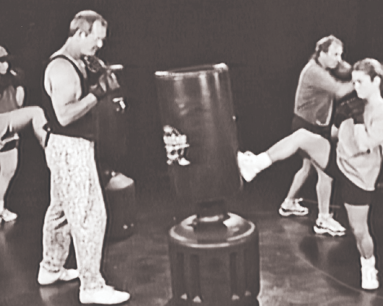 Two men training with a punching bag in a gym setting.